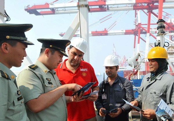 Officers from a border check station��s legal aid service department talk to sailors on board an Italian vessel about China��s entry and exit laws. The Bayuquan border check station is the first of its kind in Liaoning province to establish the legal aid service in order to ease conflicts. (Photo/Xinhua)