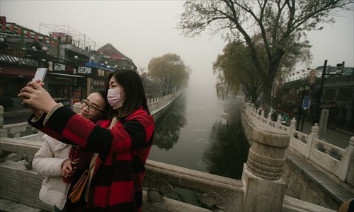 Two women take a selfie on a heavily polluted day in Beijing, November 30. (Photo: Li Hao/GT)