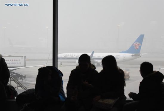 Passengers wait at Beijing Capital Airport in Beijing, capital of China, Dec. 25, 2015. Some flights were delayed due to the orange alert smog on Friday. (Xinhua)