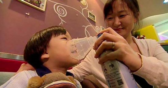 In this TV screen grab from BBC, Beijing resident Li Tianqin tries to get her son refreshed with a canister of Vitality Air's fresh air. CHINA DAILY