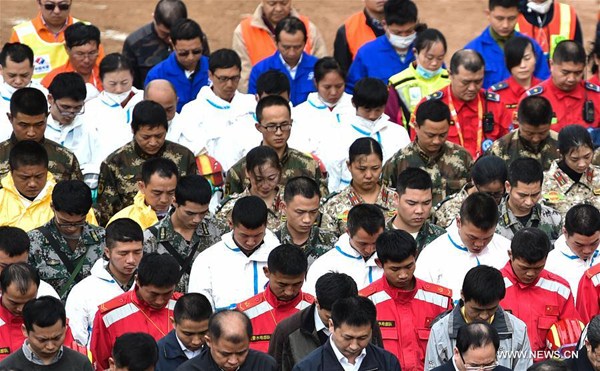 Rescuers mourn for the victims at the landslide site at an industrial park in Shenzhen, south China's Guangdong Province, Dec. 26, 2015. So far only one man has been pulled from the debris. The death toll is confirmed at seven, with 75 still unaccounted for. Rescue work continues although their chance of survival dims with time. (Xinhua/Mao Siqian)
