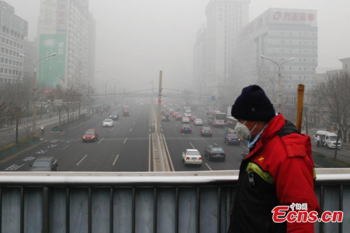 A resident walks through an overpass amid heavy smog and thick fog in Beijing, Dec. 25, 2015. (Photo: China News Service/Sheng Jiapeng)