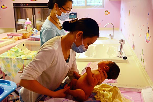 A nurse tends to a newborn after giving the infant a bath at the Heyi Confinement Center in Xiamen, Fujian province. (Photo/China Daily)