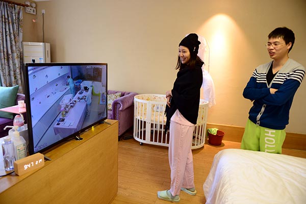 A couple watch their newborn on a TV screen at the Heyi Confinement Center in Xiamen, Fujian province. The center takes in only 20 pairs of mothers and babies at a time and charges 48,000 yuan ($7,400) to 198,000 yuan per month. (Photo/China Daily)