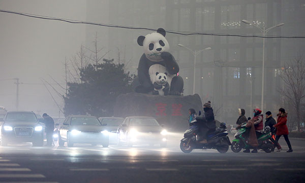 Motorists turn on their fog lights due to severe smog in Beijing on Tuesday morning. WANG ZHUANGFEI/CHINA DAILY