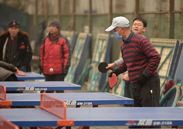 People play table tennis amid the heavy smog in Beijing's Chaoyang district on Wednesday. WEI XIAOHAO/CHINA DAILY