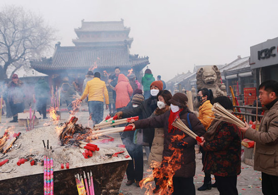 Buddhists wear masks to ward off heavy smog as they offer incense at the Daci Temple in downtown Baoding on Dec 25, a traditional day of prayer in the Chinese lunar calender. (Photo: China Daily/Zou Hong)