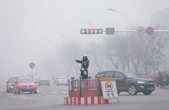 A police traffic officer wears a mask at a crossroads in Baoding, Hebei province, on Dec 25. Lingering smog prompted local authorities to launch a month-long pollution red alert in the city. Photo: China Daily/Zou Hong)