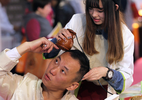 A male customer learns how to use skin care products at an industry expo in Beijing. (Photo/China Daily)