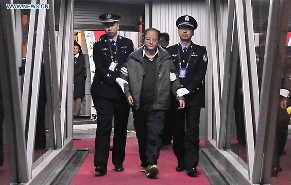 Pei Jianqiang, one of China's most wanted economic fugutives, is escorted by policemen at Capital International Airport in Beijing, capital of China, Jan. 1, 2016. Fleeing abroad in 2009, the 48-year-old former manager of China International Enterprises Cooperative's import and export department is one of the 100 economic suspects on a list wanted worldwide by the Interpol's National Central Bureau of China, including 77 men and 23 women allegedly involved in corruption. The list is part of China's Sky Net campaign to repatriate corruption suspects fleeing overseas. (Photo: Xinhua/Li Xin)  