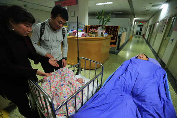 A baby girl, the first newborn in Beijing this year, meets her family at the Beijing Obstetrics and Gynecology Hospital on Jan 1. The parents said they have plans for a second child.(Photo: China Daily/Fu Ding)