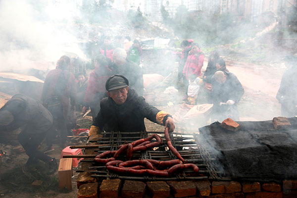 People smoke sausages in the open air in Dazhou, Sichuan province, on Dec 27. (Photo: China Daily/Zhang Ji)