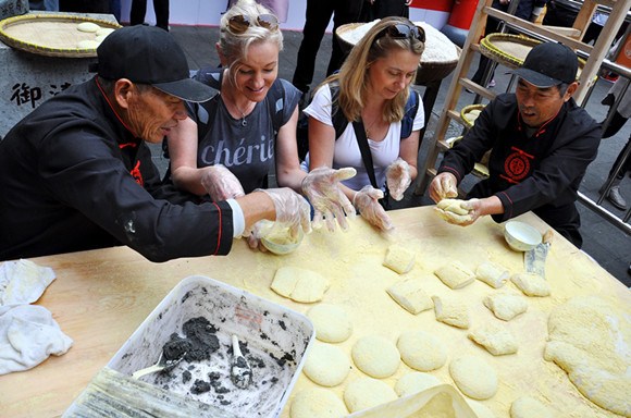 Tourists learn to make ciba, a traditional form of glutinous rice cake, during a Chinese snack food festival in Shanghai in November. (Photo: China Daily/Zhou Dongchao)