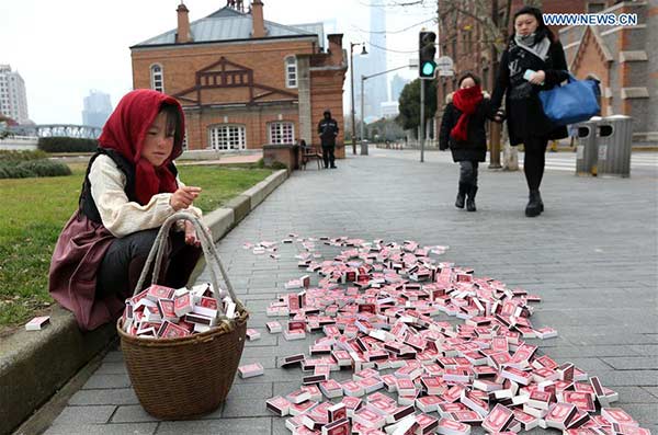 A little match girl sits with matches before her at the bund area in Shanghai, Jan 12, 2016. (Photo/Xinhua)