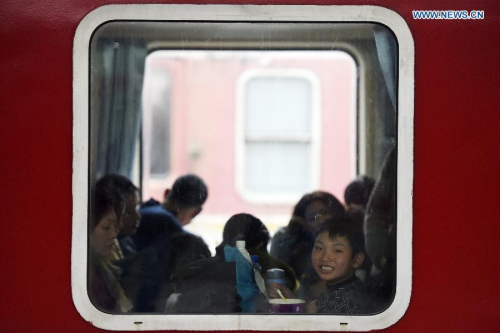 A boy on a train home looks out of the window at the railway station of Hangzhou, capital of east China's Zhejiang province, Feb 3, 2015. (Photo: Xinhua/Ju Huanzong)
