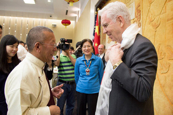 Living Buddha Shingtsa Tenzinchodrak (left) presents a Tibetan Kha Ta to US-China Partnerships Chairman Charles Foster (right) and while Foster's wife and actress Lily Chen Foster looks on. (Photo: China Daily/May Zhou