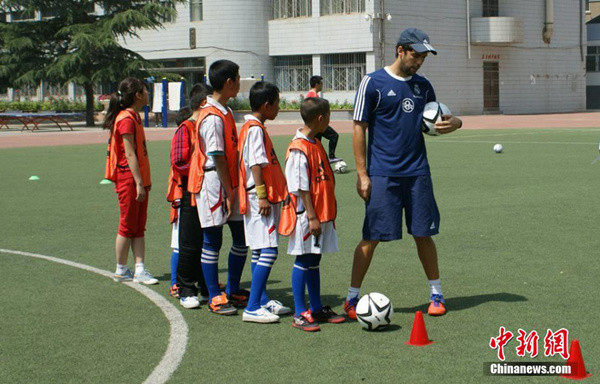 A coach from Real Madrid teaches children soccer in Lanzhou, Gansu province in June 2014. (File photo/Chinanews.com)