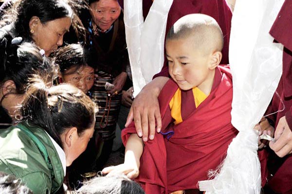 Dedrug-Jamyangxerabpaldan (right), the reincarnated soul boy of the 5th living Buddha Dedrug-Jampalgalsanggyatso, who passed away in March 2000, disperses his blessings on a recent day in Draipung Temple by touching people's heads. The temple is in Lhasa, capital of the Tibet autonomous region. The 7-year-old boy became the incarnated successor of the 5th living Buddha following a 10-year search. (Photo provided to China Daily)