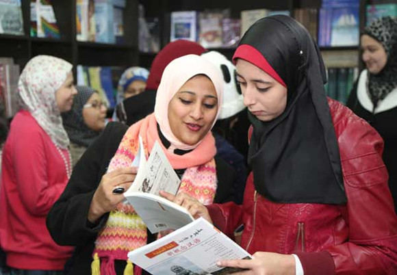 Egyptian youths browse through Chinese books translated into Arabic during a ceremony marking the start of China Book Week in Cairo, on Tuesday.(Photo: China Daily/Hou Liiqing)