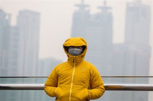 A woman protects herself against the cold and pollution on a pedestrian bridge in this file photo taken on December 15, when the city reported its worst air quality of the winter.(Jia Yanan)