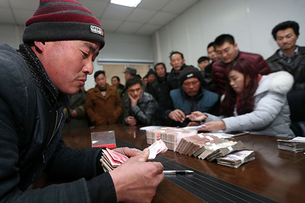 A rural migrant worker receives his wages with the help of local government authorities in Huaibei, Anhui province, on Friday. (Photo: China Daily/Wang Shanchao)