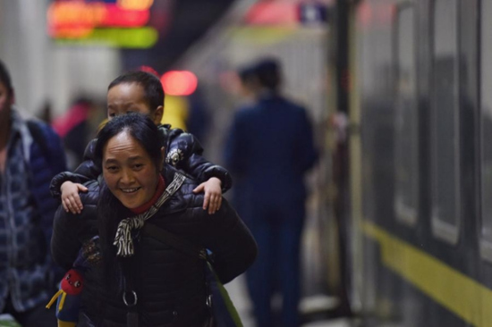 A woman carries a child to a train at Shenzhen, South China's Guangdong province, heading for Chengdu, Southwest China's Sichuan province, Jan 24, 2016. (Photo/Xinhua)