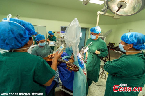 A patient plays the guitar while undergoing surgery on his head at a hospital in Shenzhen City, South Chinas Guangdong Province, Jan. 25, 2016. (Photo/IC)