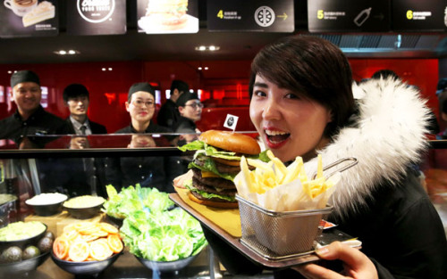 A customer shows a self-made burger at McDonald's first Experience of the Future restaurant in Beijing.(Photo/China Daily)
