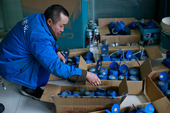 Plumber Qiu Tianpei prepares new water meters at the maintenance station where he works in Jing'an district. His fingers are bandaged because of heavy work in difficult conditions.(XIAO JUNWEI/CHINA DAILY)