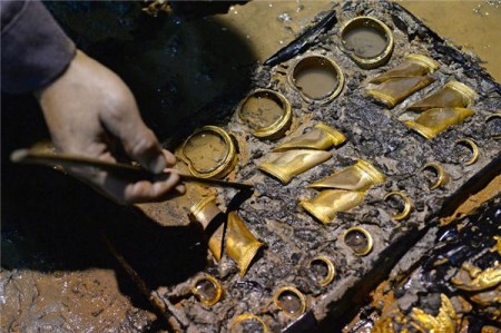 An archaeologist cleans the hoof-shaped ingots from the tomb of "Haihunhou" (Marquis of Haihun) in Nanchang, capital of East China's Jiangxi province, Nov 17, 2015. (Photo/Xinhua)
