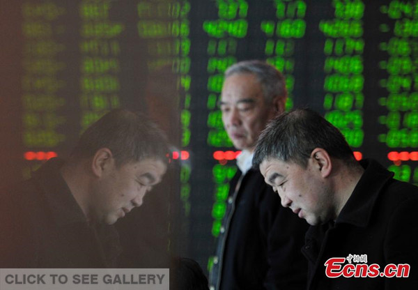 Investors look at an electronic board showing stock information at a brokerage house in Taiyuan, north China's Shanxi Province, Jan. 4, 2016. 