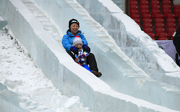 A mother and child slide down an ice slope at the Happy Ice and Snow Carnival. (Photo/provided to chinadaily.com.cn)