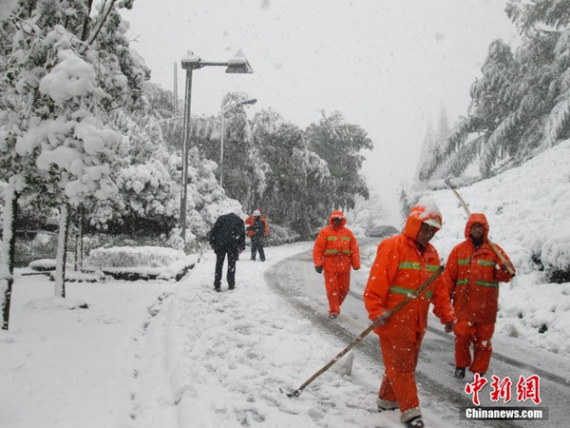 Workers clean snow-covered road in Hangzhou, East China's Zhejiang province, on Thursday. (Photo/chinanews.com)