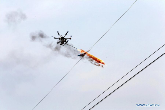 A drone burns off waste and sundries on the wire in Puyang, Central China's Henan province, March 17, 2015. (Photo/Xinhua)