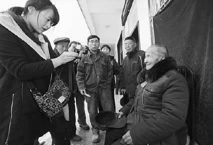 A community worker takes a profile photo for a resident who is covered by the basic pension insurance system in Mengcheng, Anhui province, in December. Hu Weiguo / For China Daily