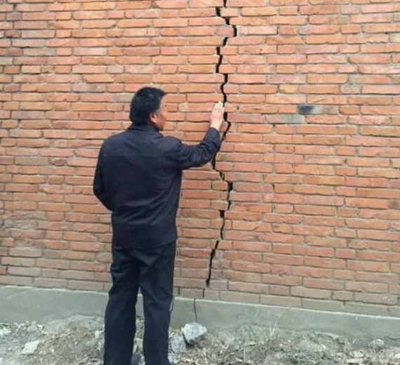 Lu Haisu, a resident of Zhailixi village, Hebei province, examines a crack in the wall of his house. (GUO YARU/XINHUA) Lu Haisu, a resident of Zhailixi village, Hebei province, examines a crack in the wall of his house. (GUO YARU/XINHUA)