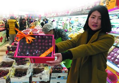 A woman holds a box of foreign fruits in a supermarket of Qingdao. (Photo/Qingdaonews.com) 