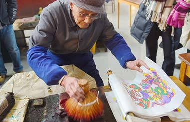 Guo Taiyuan, 91, shows his skill of making woodprint pictures at a museum in Kaifeng, Henan province. Photo provided to China Daily