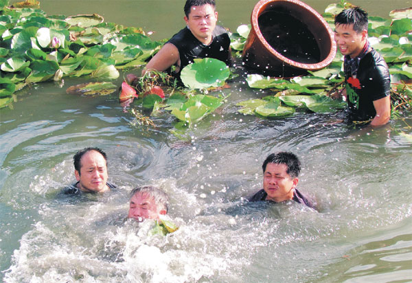 Yu Dan (middle) and student researchers attempt to plant aquatic seedlings in the bed of Liangzi Lake. (Photo provided to China Daily)