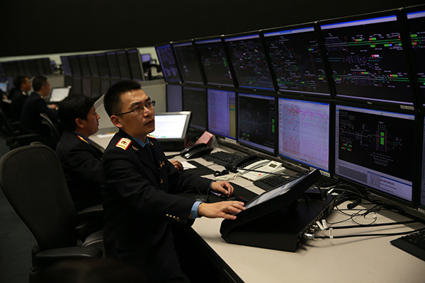 Zhang Bo(right), 34, train conductor at Beijing railway administration, stares at a monitor to track status of trains on Feb 2, 2015. (Photo by Zou Hong/China Daily)