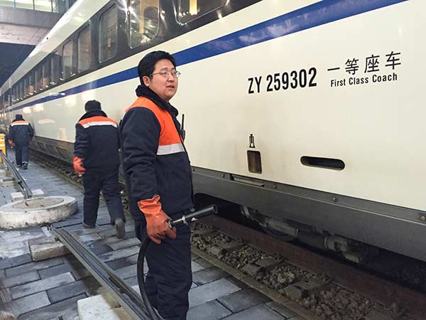 Li Jian holds a hose to fill up the water tank on Feb 2 at Beijing West Railway Station. Photo by Liu Wei/chinadaily.com.cn