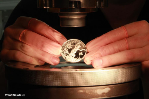 A staff member of the Royal Mint checks a coin of lunar Year of the Monkey at a workshop in Llantrisant, Britain, Feb. 1, 2016. (Photo: Xinhua/Wu Congsi)
