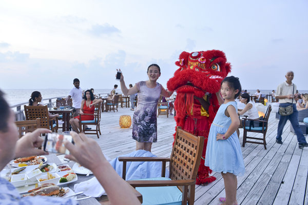 Chinese tourists take photo with lion dancers during a sea outing in the Maldives on Sunday at the start of the ongoing Spring Festival holiday. (Photo/XINHUA)