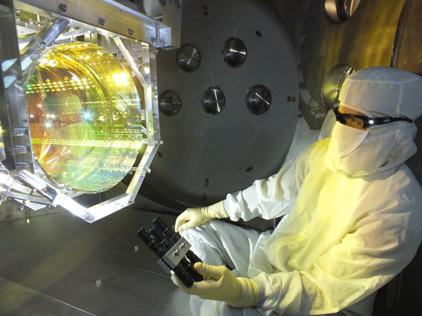 A technician inspects one of the U.S. laboratory's core optics (mirrors) by illuminating its surface at different angles. Caltech/MIT/LIGO Lab
