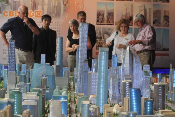 Foreigners look at real estate project models at a central business district (CBD) in Beijing. (File photo)
