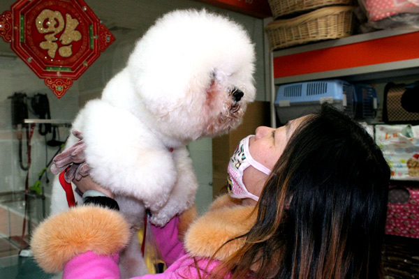 A resident of Suzhou, Jiangsu province, bids farewell as she leaves her dog at a pet hotel last week while preparing to leave for the Spring Festival holiday.(Photo by Wang Jiankang/China Daily)