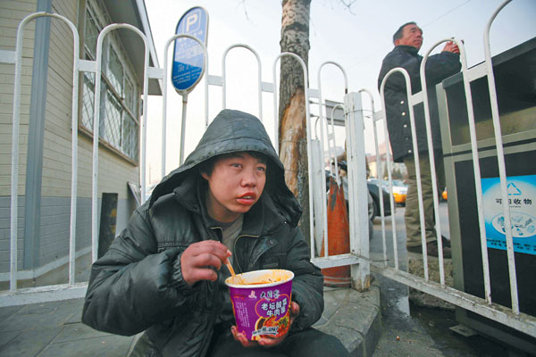A teenager, unsure of his identity and living on a street corner near Beijing Railway Station, is helped by China Daily photographer Wang Jing on Tuesday before being taken to a care center. (Photo by Wang Jing/China Daily)