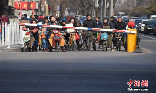 E-bikers and cyclists wait at a newly-installed barrier gate in Taiyuan, Shanxi Province, on Wednesday. Local traffic officials set up the gates to curb the rampant disregard for traffic rules among cyclists. (Photo/China News Service)