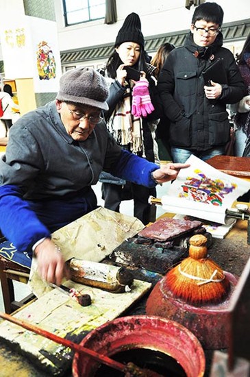 Guo Taiyun demonstrates his skills in making woodblock prints in a museum in Kaifeng, Henan province. (Photo by Liu Xiangrui/China Daily)