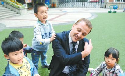Nigel Jones play with children at a pre-school in Chengdu in 2012. (Photo/West China City Daily)